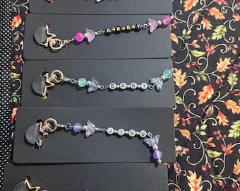 May include: Five beaded keychains with star-shaped clasps. Each keychain features butterfly charms, colorful beads, and letter beads spelling out words: "ROMANCE", "A B B Y", "BABY", "JINU", and "MYSTERY".