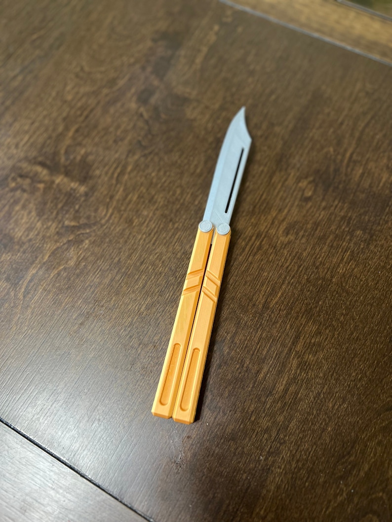 May include: A silver and orange butterfly knife with a textured handle.