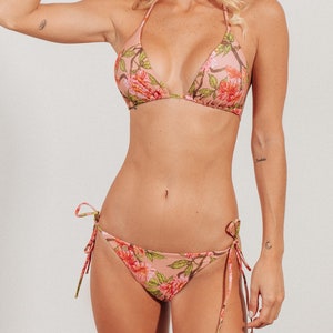 May include: A pink floral print bikini top and bottom with adjustable ties. The bikini top is a triangle style and the bottom is a cheeky style.