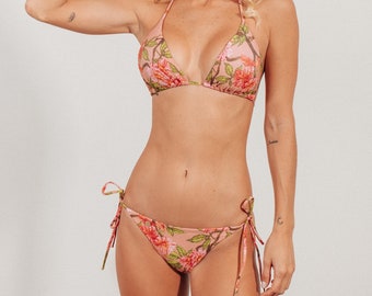 Könnte beinhalten: Ein rosafarbenes Bikini-Oberteil und -Unterteil mit floralem Druck und verstellbaren Bändern. Das Bikini-Oberteil ist im Dreieckstil gehalten, das Unterteil im knappen Stil.