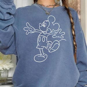 May include: A blue sweatshirt with a white outline of Mickey Mouse in a walking pose. The sweatshirt has a relaxed fit and long sleeves.