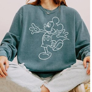 May include: A teal blue sweatshirt with a white outline of Mickey Mouse.