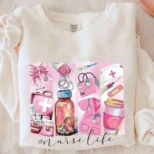 May include: A white sweatshirt with a pink graphic design featuring medical supplies and the text "#nurselife".
