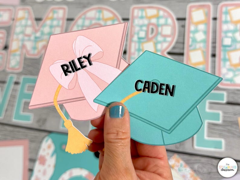Puede incluir: Dos gorros de graduaci&oacute;n, uno rosa con un lazo y el nombre "RILEY" y otro azul verdoso con el nombre "CADEN".