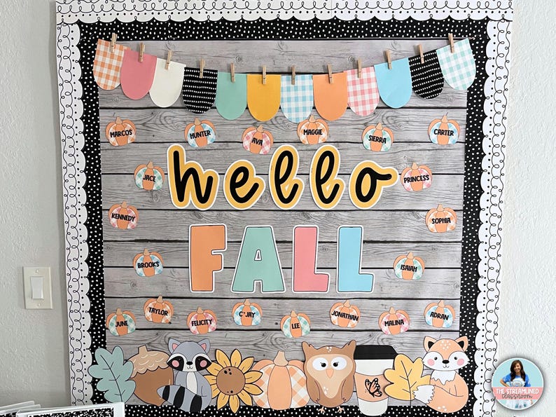 May include: A classroom bulletin board decorated for fall with a wooden plank background. The board features a banner with colorful scalloped shapes, the words "hello fall" in yellow and black lettering, and student names written on small pumpkin cutouts.