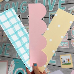 Puede incluir: Tres tiras de papel con diferentes patrones para un tablero de anuncios de clase. Las tiras son de cuadros azules y blancos, rosa con bordes festoneados y amarillo con lunares blancos. El texto "Long Live Memories" es visible en el fondo.