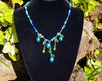 Multi-beaded blueberry necklace surrounded with tiny leaves.