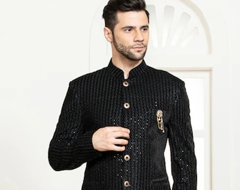 Könnte beinhalten: Ein schwarzer Blazer mit strukturiertem Design und goldenen Knöpfen. Der Blazer hat einen Stehkragen und einen einzigen Knopfverschluss vorne. Das Model trägt eine schwarze Hose und schwarze Schuhe.