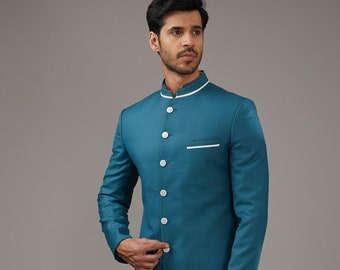 Puede incluir: Una kurta de manga larga azul turquesa con cuello blanco y botones blancos. La kurta tiene un cuello mandarín y un solo bolsillo en el pecho izquierdo. El modelo lleva pantalones blancos y mocasines marrones. El texto "URdesigners" es visible en la parte inferior derecha de la imagen.