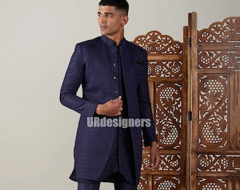 Puede incluir: Un traje azul marino de tres piezas con una chaqueta estampada, pantalones a juego y un chaleco. La chaqueta tiene un cuello mandarín y cierre de botones. El traje lo lleva una persona de pie frente a una pantalla de madera.