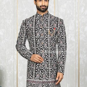 May include: A black velvet kurta with a white and silver floral pattern. The kurta has a mandarin collar and a button closure. The kurta is embroidered with silver thread and has a pink and white border at the bottom.
