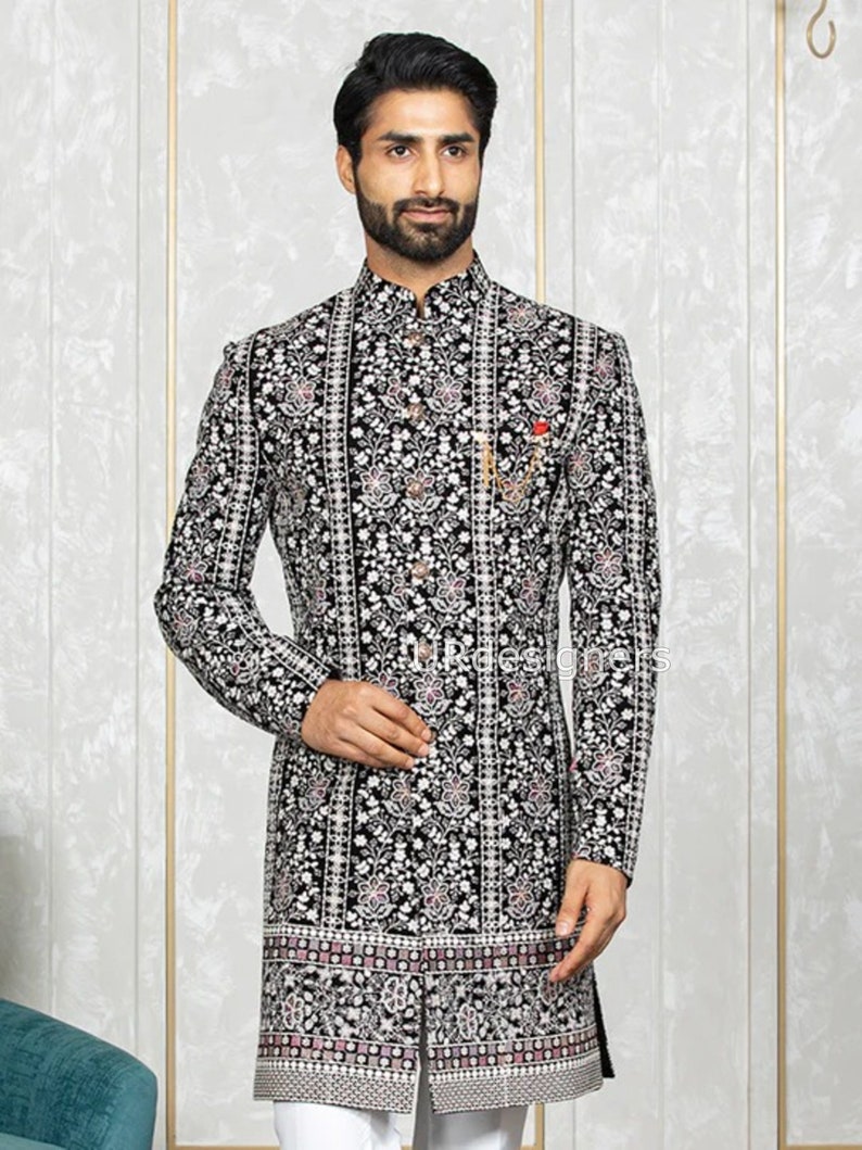 May include: A black velvet kurta with a white and silver floral pattern. The kurta has a mandarin collar and a button closure. The kurta is embroidered with silver thread and has a pink and white border at the bottom.