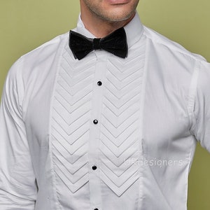 May include: A white dress shirt with a pleated front and a black bow tie. The shirt has a pointed collar and long sleeves.