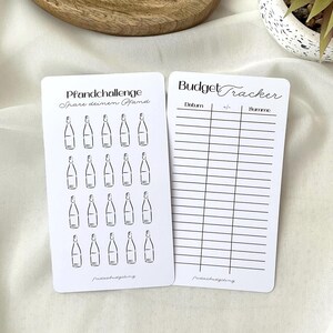 May include: Two white cards with black text and illustrations. One card says "Pfandchallenge" and features bottle drawings. The other card is a "Budget Tracker" with columns for date, +/- and sum. Both cards have the text "fridasbudgeting."