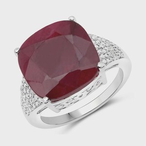May include: A silver ring with a large, red, cushion-cut ruby gemstone surrounded by smaller, white gemstones.
