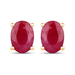 May include: A pair of oval-shaped ruby earrings set in gold.