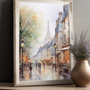 May include: A watercolor painting of a Parisian street scene with a view of the Eiffel Tower in the distance. The street is lined with buildings and trees, and there are people walking with umbrellas. The painting is framed in a white frame.