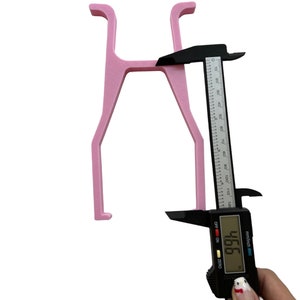 May include: Pink plastic H-shaped object being measured with a digital caliper. The caliper reads 466 mm.
