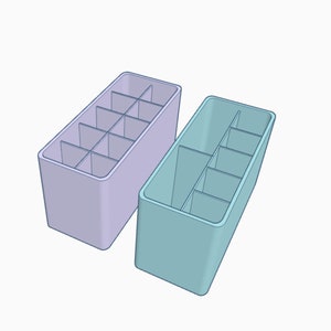 May include: Two rectangular storage organizers with multiple compartments. One is light purple and the other is light blue.