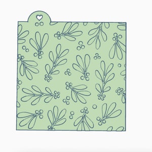 May include: A green stencil with a pattern of blue mistletoe leaves and berries. The stencil has a heart-shaped cutout at the top.