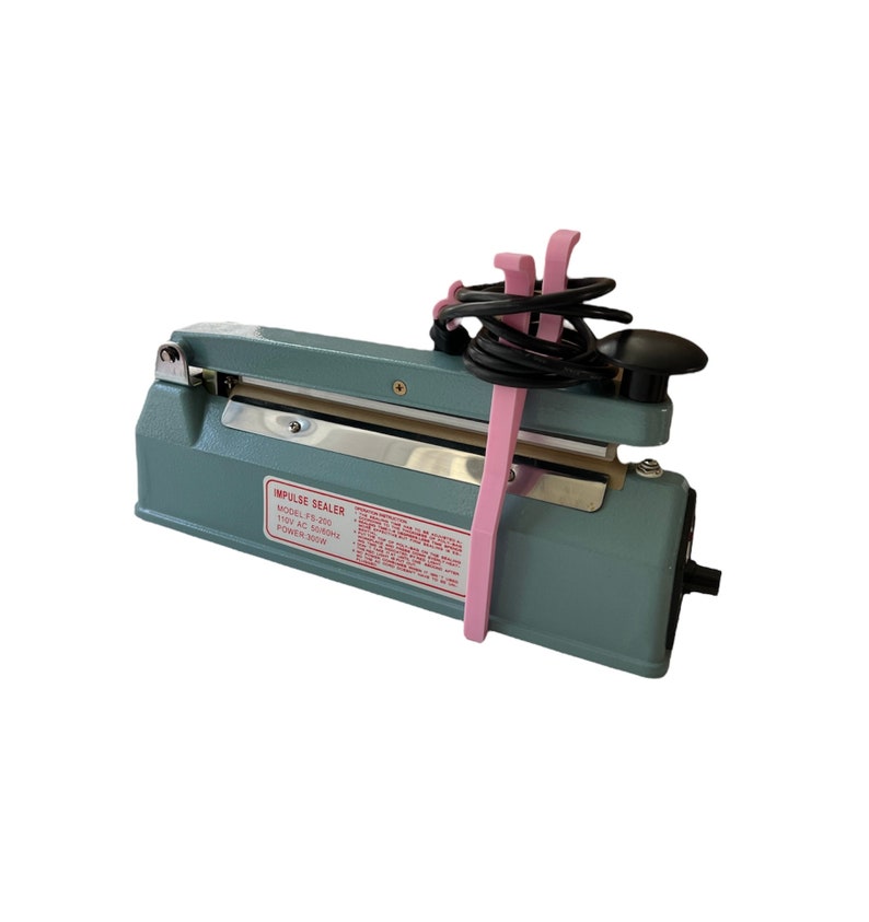 May include: A grey impulse sealer with a black power cord and pink cord holders. The sealer has a silver sealing bar and a label that reads "Impulse Sealer Model: FS-200 110V AC 50/60Hz Power: 300W".