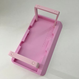 May include: Pink plastic cookie tray with two handles and the text "24 Cookies" printed on the front.