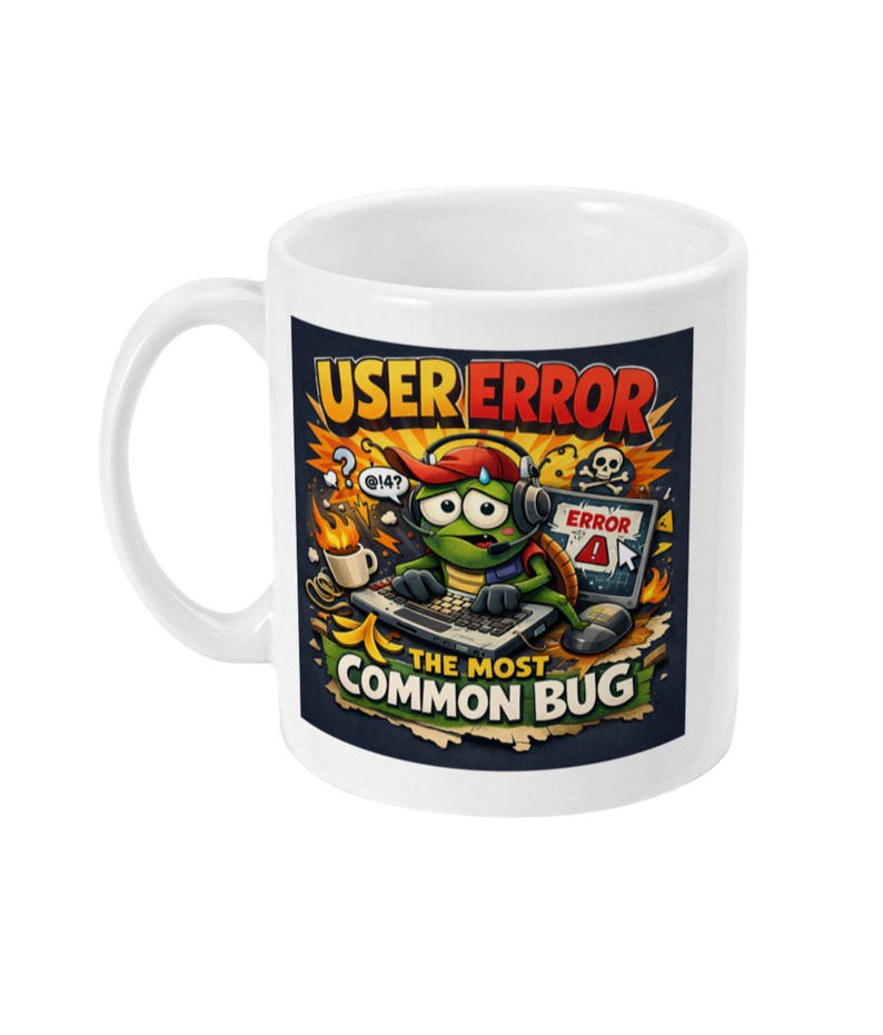May include: White ceramic mug with a colorful cartoon design. The design features a turtle wearing a headset and hat, working on a laptop with the text "USER ERROR" and "THE MOST COMMON BUG". A skull and error message are also included.