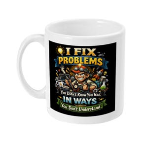 Op de afbeelding: Witte keramische mok met een humoristische afbeelding. Het ontwerp toont een stripfiguur met een bril en gereedschap, samen met de tekst "I FIX PROBLEMS" en "You Didn't Know You Had, IN WAYS You Don't Understand."