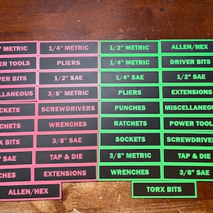 May include: A collection of black and pink and black and green tool labels with white text. The labels are organized in rows and columns, with text such as "1/2 SAE", "Sockets", and "Allen/Hex".