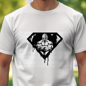 Peut inclure: Un t-shirt blanc avec un motif noir et blanc d'une figure musclée portant un casque avec un motif de drapeau américain. La figure est dans un losange avec des bords qui coulent.