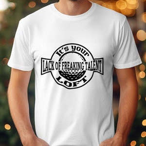 May include: White t-shirt with a black and white graphic design of a golf ball with the text "It's your lack of freaking talent loft".