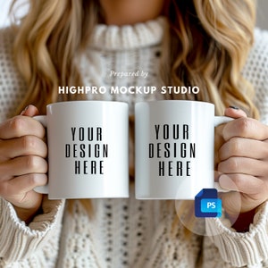 Puede incluir: Dos tazas de cerámica blanca con texto negro que dice "Your Design Here". Las tazas están sostenidas por una persona que lleva un suéter blanco.