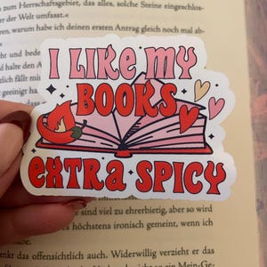 Könnte beinhalten: Ein rosa und roter Aufkleber mit einem Buch und einer Chilischote. Der Aufkleber sagt "Ich mag meine Bücher extra scharf".