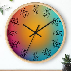 May include: A round wooden clock with a rainbow gradient background. The clock face features black dancing bear silhouettes around the edge. The clock hands are black.