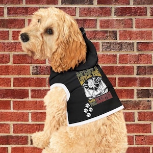 May include: A black dog hoodie with a white trim and a graphic print that says "Spent a little time on the mountain" with a cartoon image of a dog hiking. The hoodie is on a light brown dog.