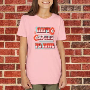 May include: Pink t-shirt with a retro-style graphic that says "Ain't No Time To Hate" with flowers and a blue background.