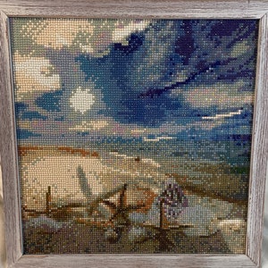 May include: A framed diamond painting depicting a seascape with a cloudy sky, a beach, and a wooden fence in the foreground.