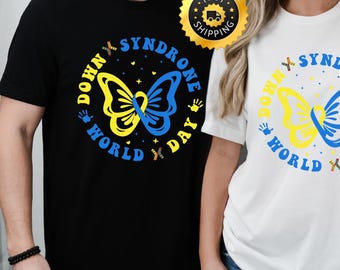 May include: Two t-shirts featuring a butterfly design and the text "Down Syndrome World Day". The butterfly is yellow and blue, representing the Down Syndrome awareness ribbon colours.