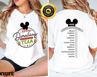May include: White t-shirt with a black Mickey Mouse head and the text "Disney Drinking Around the World Team". The back of the shirt has a checklist with the text "Drinking Around the World" and a list of countries to check off.