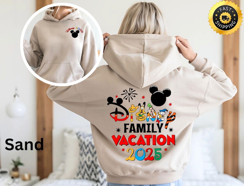 Puede incluir: Una sudadera con capucha de color arena con un gran estampado gr&aacute;fico en la espalda. El gr&aacute;fico presenta a Mickey Mouse y otros personajes de Disney con el texto "Disney Family Vacation 2025".
