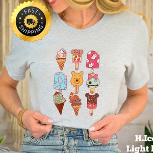 May include: Light blue t-shirt with a graphic of various ice cream pops and cones featuring popular cartoon characters. The ice cream pops and cones are arranged in a grid pattern.