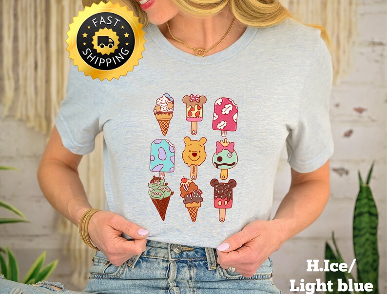 May include: Light blue t-shirt with a graphic of various ice cream pops and cones featuring popular cartoon characters. The ice cream pops and cones are arranged in a grid pattern.