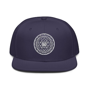 May include: A navy blue baseball cap with a white embroidered Sri Yantra symbol on the front.