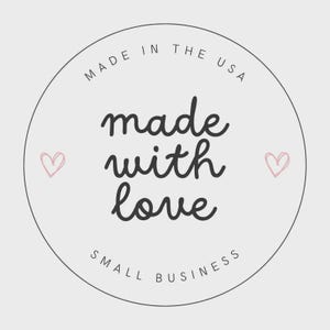May include: A circular sticker with a light gray background and a thin black border. The text reads MADE IN THE USA at the top, made with love in the center in a cursive font, and SMALL BUSINESS at the bottom. Two small pink hearts flank the text.