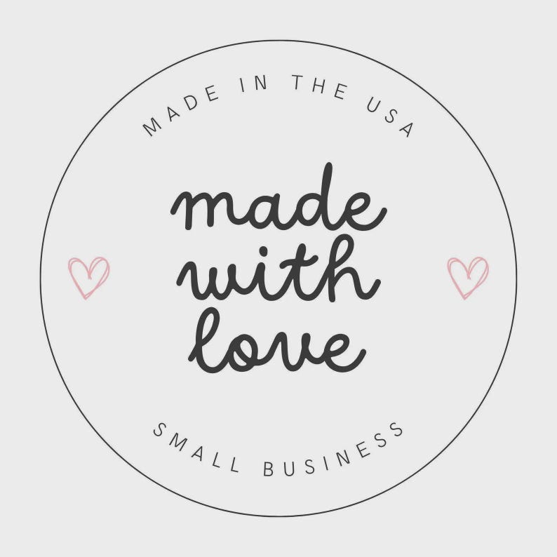 May include: A circular sticker with a light gray background and a thin black border. The text reads MADE IN THE USA at the top, made with love in the center in a cursive font, and SMALL BUSINESS at the bottom. Two small pink hearts flank the text.