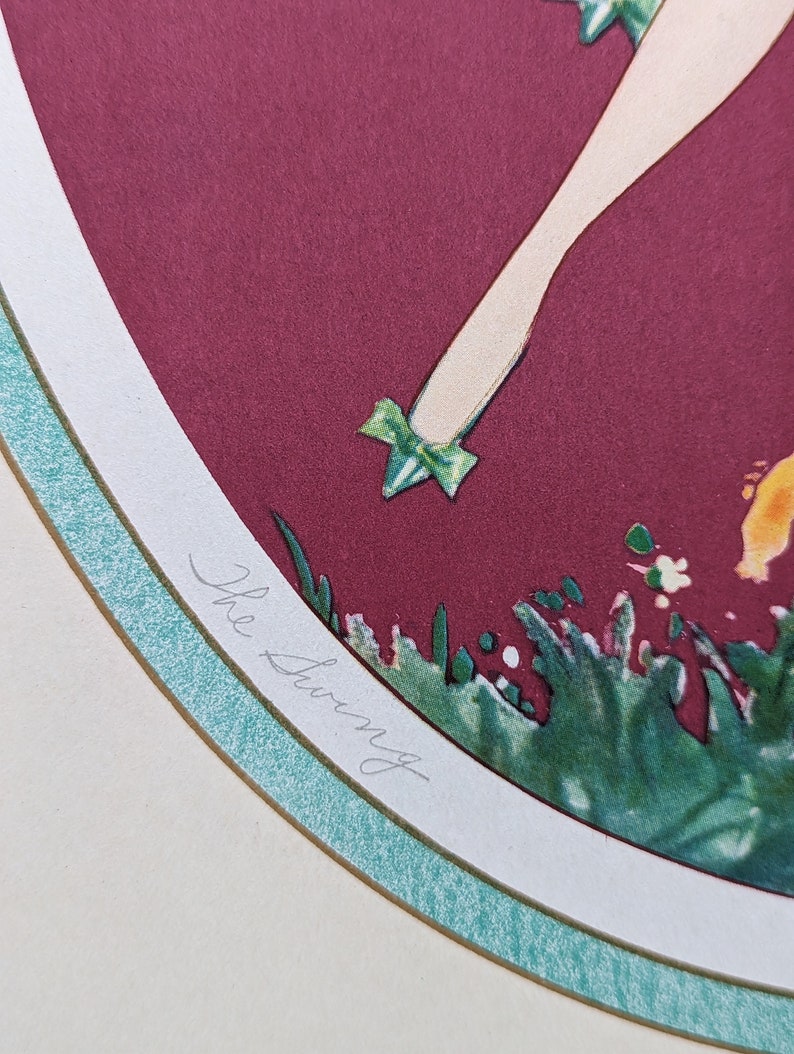 May include: An art print titled "The Swing" features a stylized illustration of a figure with a leg and foot adorned with a green bow. The artwork is set against a burgundy background, framed by a white and teal border.
