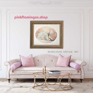 A staged interior scene featuring 'La Belle Rose' print by Icart framed and hung above a classic beige sofa with pink pillows.