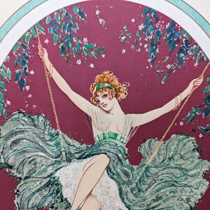 May include: Art Deco illustration of a woman on a swing. She wears a green dress and a matching headband. The background is a deep red with green foliage and white flowers. The image is framed with a white border and a teal accent.