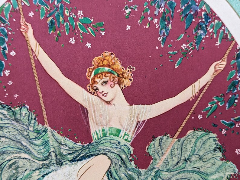 May include: Vintage art print of a woman on a swing. The woman has curly red hair, a green headband, and a flowing green dress. The background is a deep red with green foliage and white flowers.
