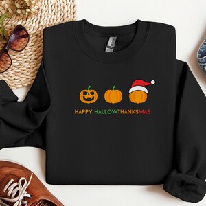 Happy Hallowthanksmas sweatshirt with pumpkins for Halloween, Thanksgiving, and Christmas